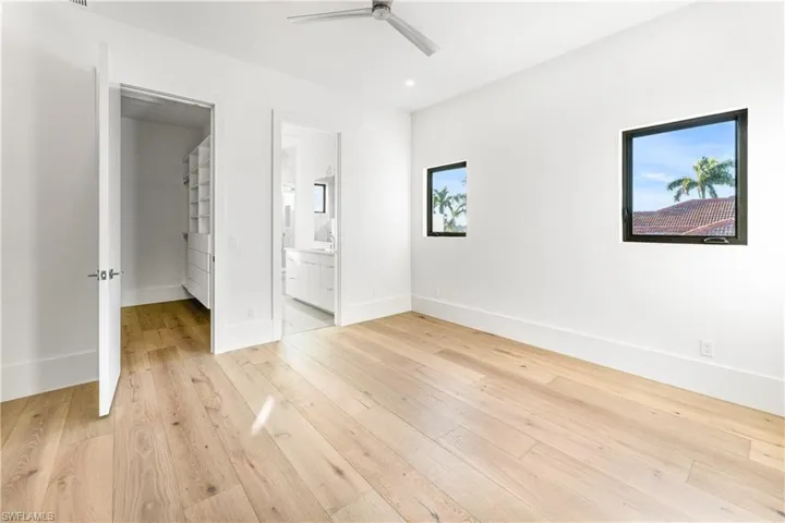 Unfurnished bedroom with light wood-style flooring, connected bathroom, and ceiling fan