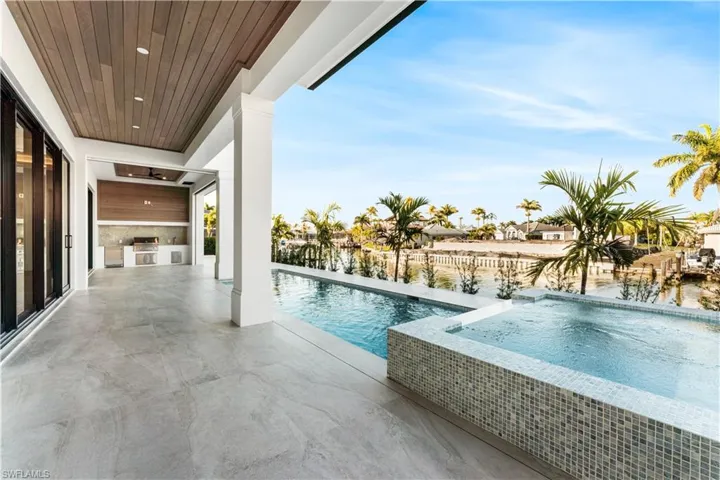 Outdoor pool with an in-ground hot tub, a patio, and an outdoor kitchen