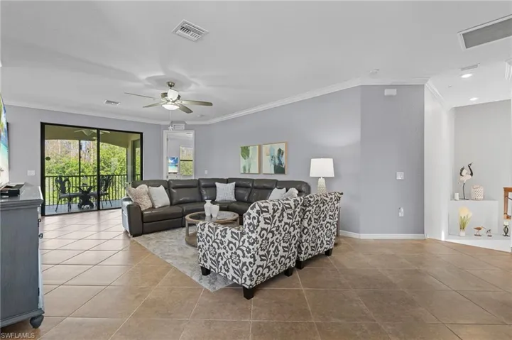 Living room with ceiling fan, light tile patterned floors, and ornamental molding