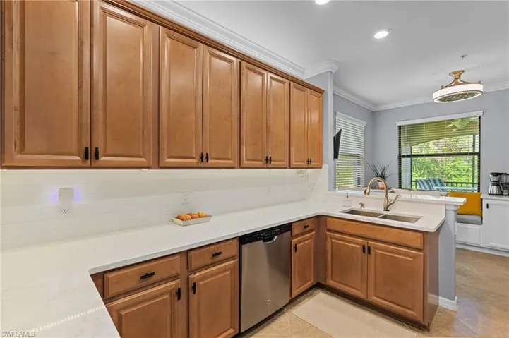 Kitchen with kitchen peninsula, stainless steel dishwasher, crown molding, and sink