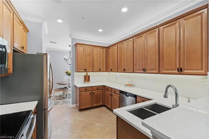 Kitchen with sink, crown molding, decorative backsplash, light tile patterned floors, and appliances with stainless steel finishes