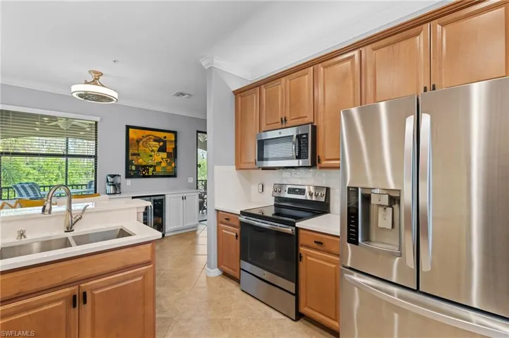 Kitchen featuring crown molding, sink, wine cooler, light tile patterned floors, and stainless steel appliances