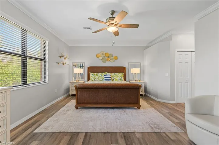 Bedroom with ceiling fan, wood-type flooring, and ornamental molding