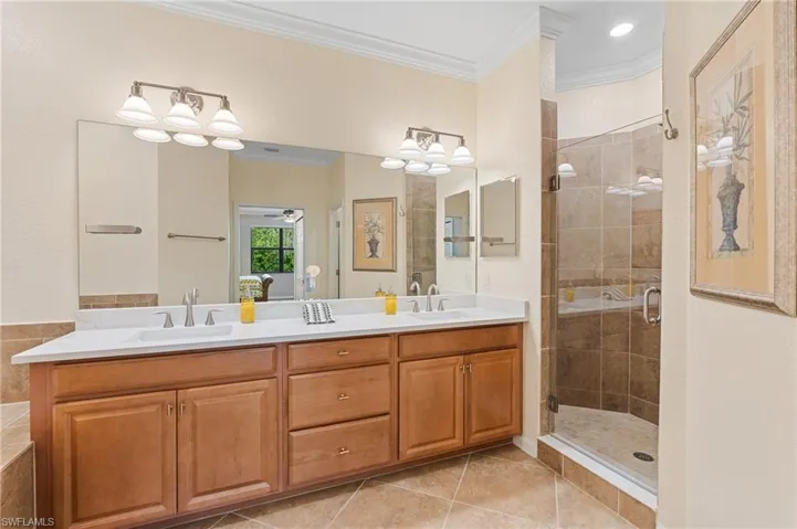 Bathroom featuring tile patterned flooring, vanity, a shower with shower door, and crown molding