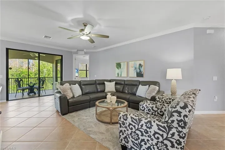 Living room with ceiling fan, ornamental molding, and light tile patterned flooring