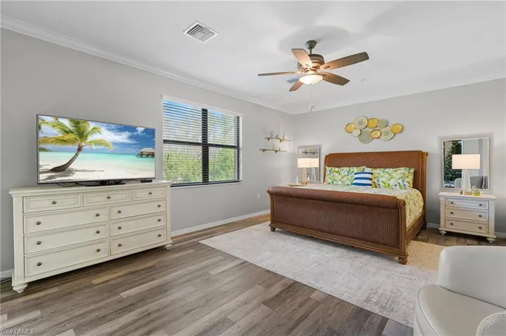 Bedroom with hardwood / wood-style floors, ceiling fan, and ornamental molding