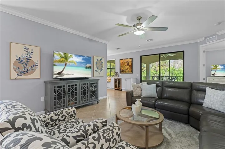 Tiled living room with beverage cooler, ornamental molding, and ceiling fan