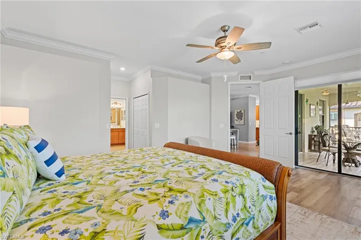 Bedroom featuring connected bathroom, access to exterior, ceiling fan, light hardwood / wood-style flooring, and ornamental molding