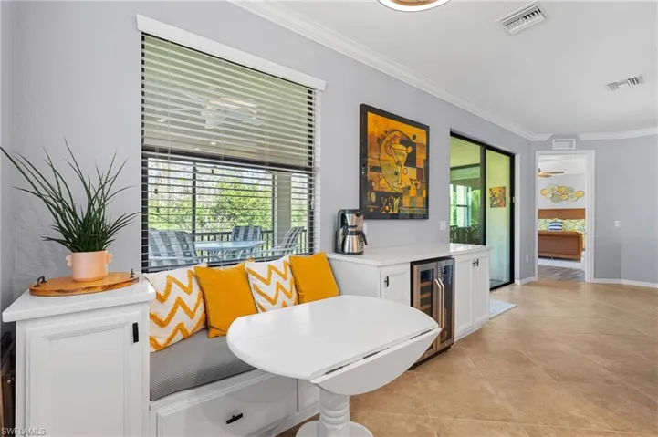 Dining room featuring ceiling fan, beverage cooler, crown molding, breakfast area, and light tile patterned flooring