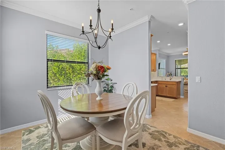 Dining area featuring light tile patterned flooring, a wealth of natural light, ornamental molding, and sink