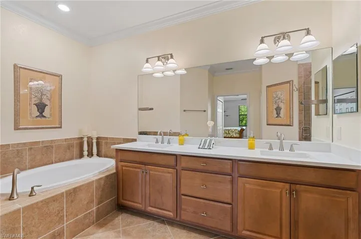 Bathroom featuring tile patterned flooring, vanity, separate shower and tub, and ornamental molding