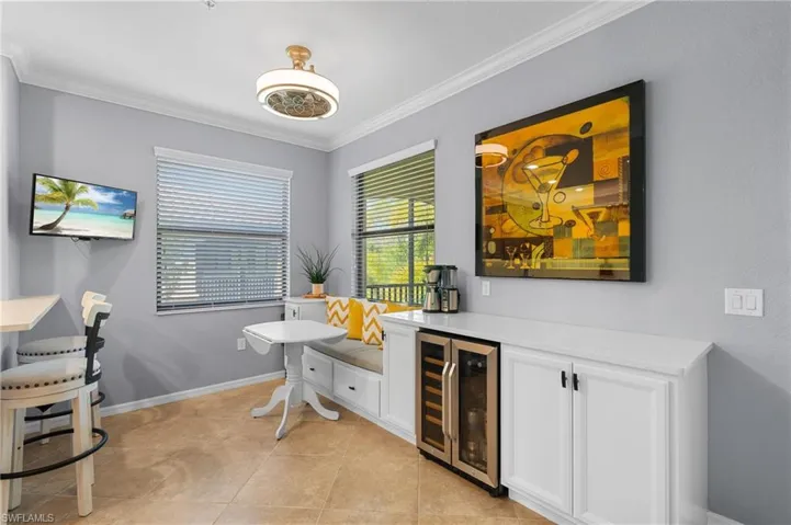 Bar featuring wine cooler, white cabinetry, crown molding, and light tile patterned floors