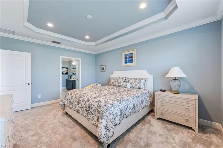 Bedroom featuring light carpet, visible vents, a tray ceiling, and ornamental molding