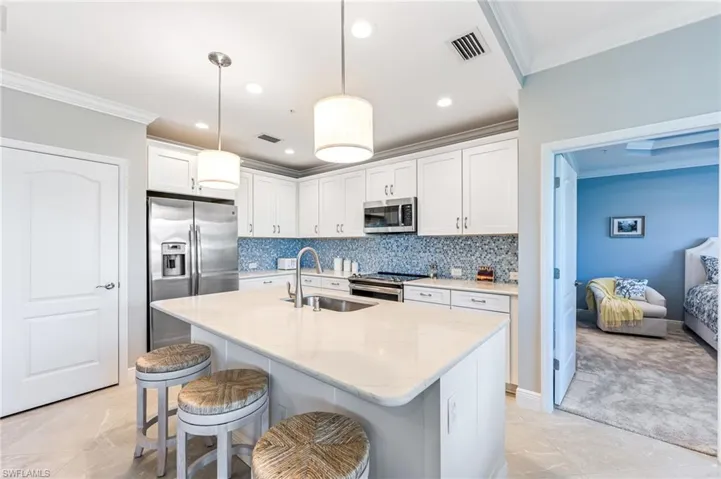 Kitchen featuring a kitchen bar, ornamental molding, visible vents, appliances with stainless steel finishes, and a sink