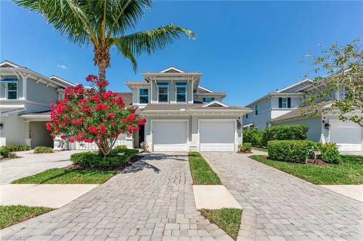 Traditional-style house featuring a garage, decorative driveway, and stucco siding
