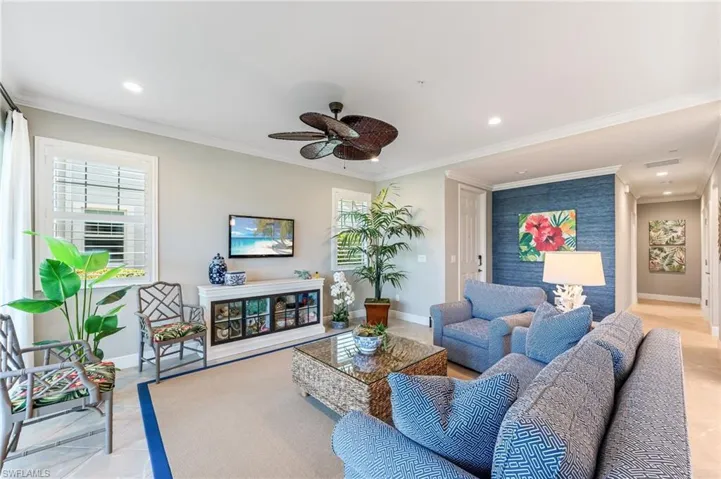 Living area featuring ornamental molding, ceiling fan, baseboards, and a healthy amount of sunlight