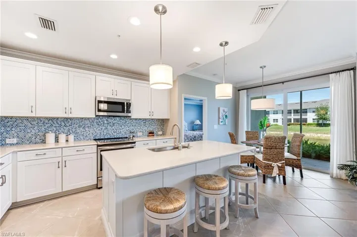 Kitchen featuring a sink, appliances with stainless steel finishes, crown molding, decorative backsplash, and light tile patterned flooring