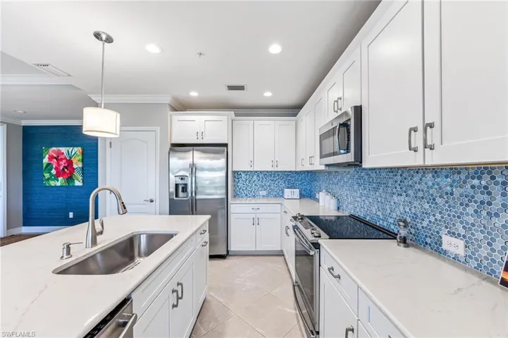Kitchen with white cabinetry, ornamental molding, visible vents, appliances with stainless steel finishes, and a sink