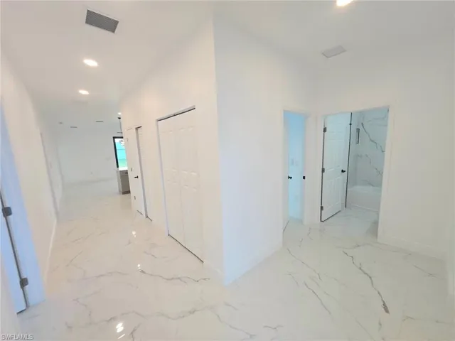 Hallway with recessed lighting and light marble finish flooring