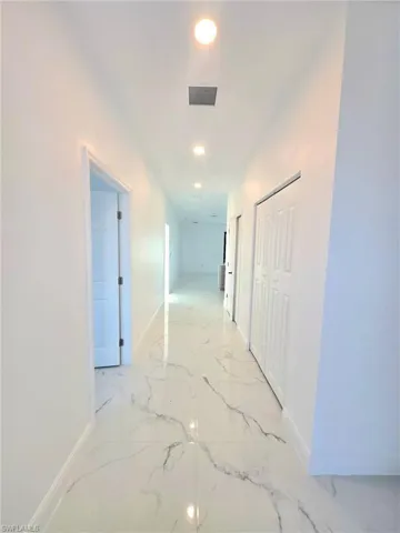 Hallway featuring recessed lighting and light marble finish floors