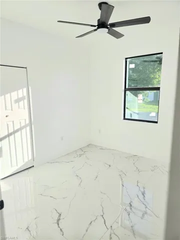 Unfurnished room with light marble finish floors and a ceiling fan