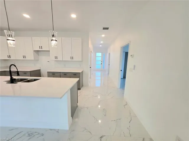 Kitchen with light marble finish floors, pendant lighting, light stone countertops, recessed lighting, and white cabinetry