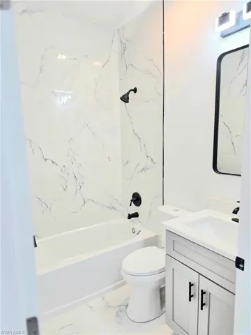 Full bathroom with vanity, tub / shower combination, and light marble finish flooring