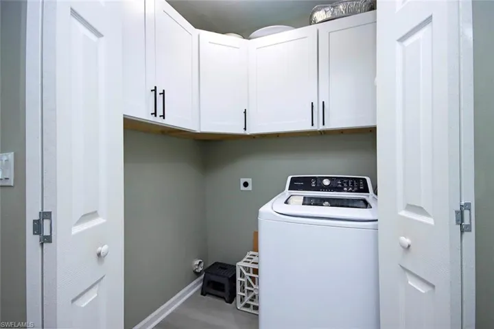 Laundry area featuring washer / clothes dryer, baseboards, wood finished floors, and cabinet space
