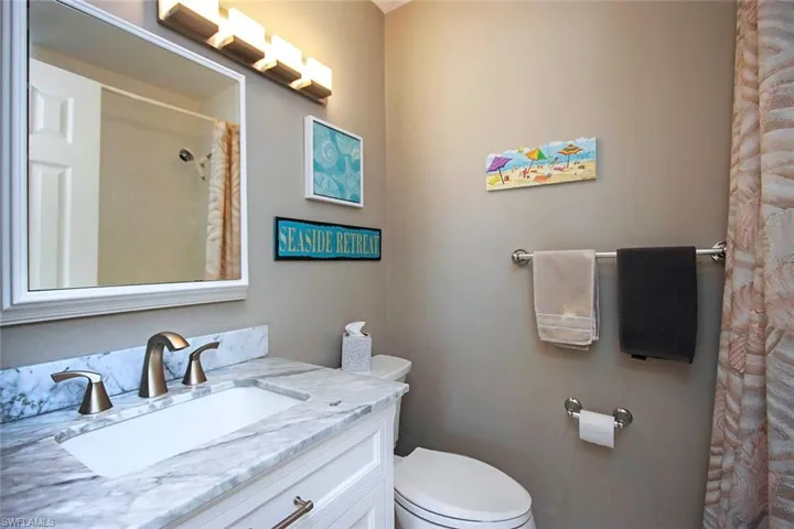 Bathroom featuring curtained shower, vanity, and toilet