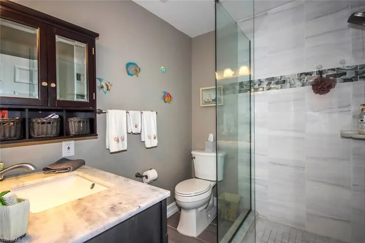 Bathroom featuring toilet, vanity, a stall shower, and tile patterned flooring