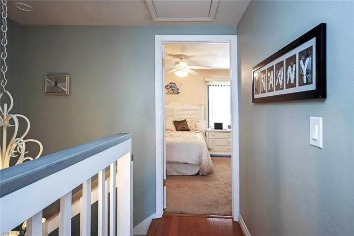 Corridor with dark wood-type flooring and an upstairs landing
