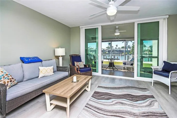 Living room with wood finished floors, floor to ceiling windows, a ceiling fan, and a water view