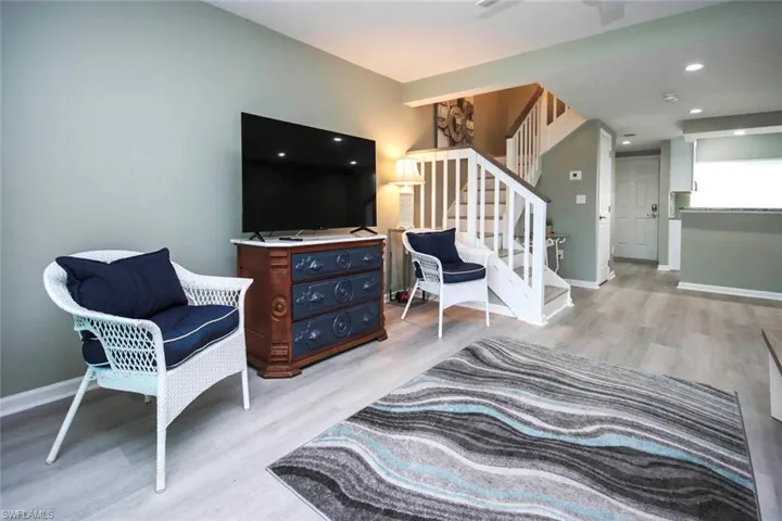 Living room featuring light wood finished floors, baseboards, and stairway