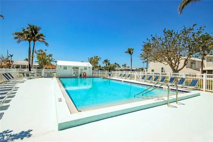 Community pool with an outbuilding, a patio area, and fence