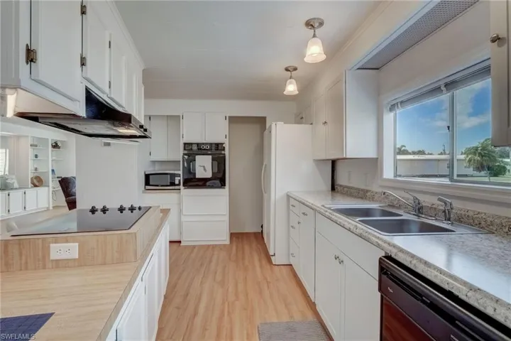 Kitchen featuring white cabinets, black appliances, and light countertops
