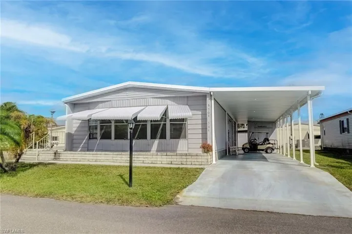 Manufactured / mobile home with a front yard, driveway, and an attached carport