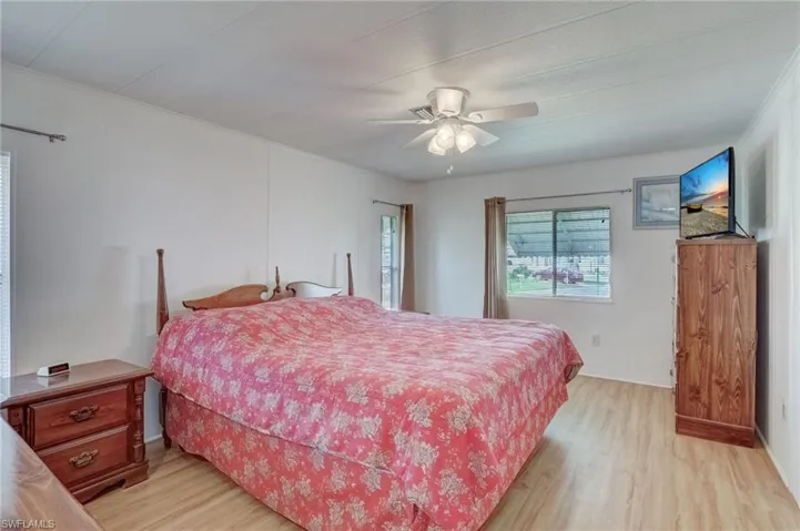 Bedroom featuring light wood-style flooring, a ceiling fan, and ornamental molding