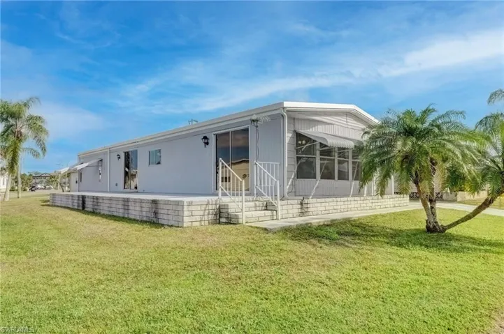 Back of property with a lawn, a sunroom, and a patio