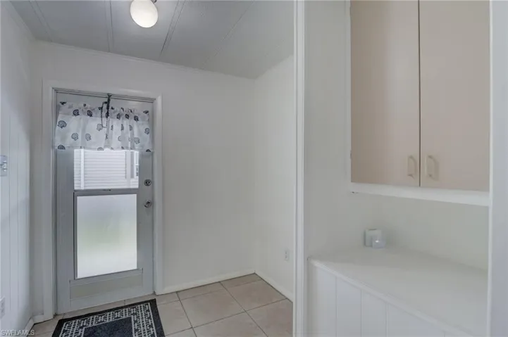 Doorway featuring tile patterned floors and crown molding