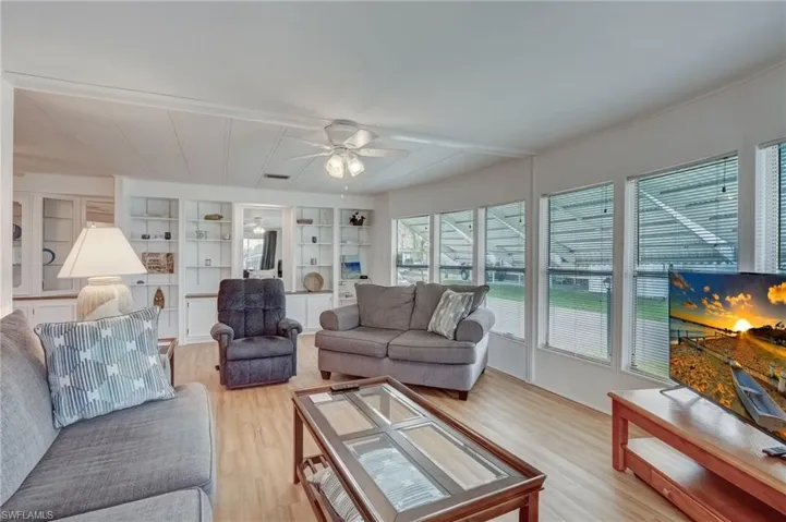 Living area with light wood-style flooring, ceiling fan, and built in features