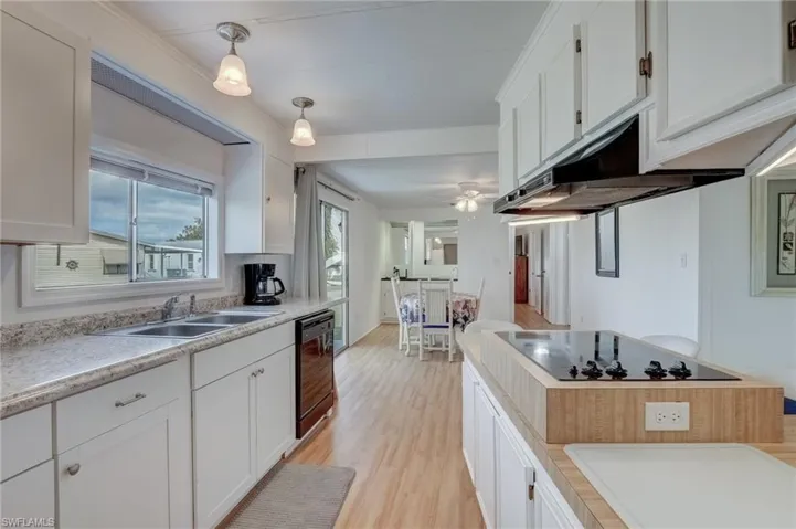Kitchen featuring white cabinets, light wood finished floors, light countertops, and black appliances