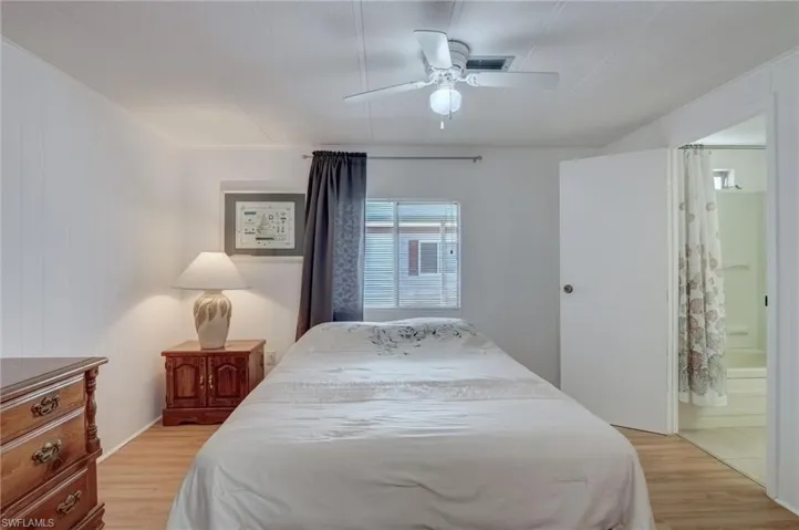Bedroom with light wood-type flooring, a ceiling fan, and ensuite bathroom