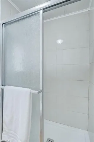 Bathroom featuring a shower stall and crown molding