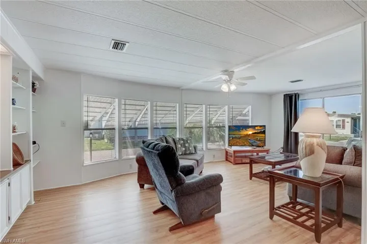 Living area featuring light wood-style flooring, plenty of natural light, and a ceiling fan