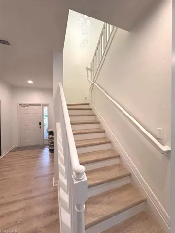 Stairs featuring wood finished floors and recessed lighting