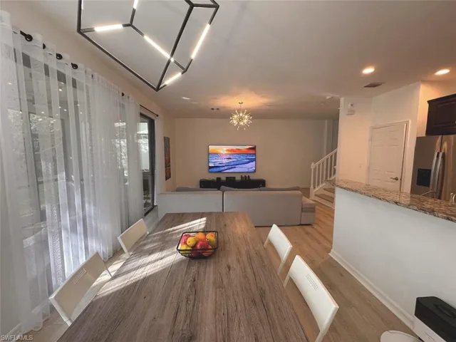 Dining room featuring a chandelier, light wood-style floors, stairs, and recessed lighting