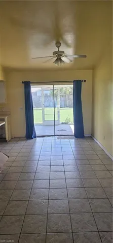 Tiled spare room with plenty of natural light and ceiling fan