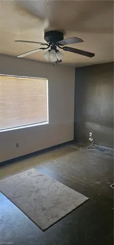 Empty room featuring a ceiling fan and concrete floors