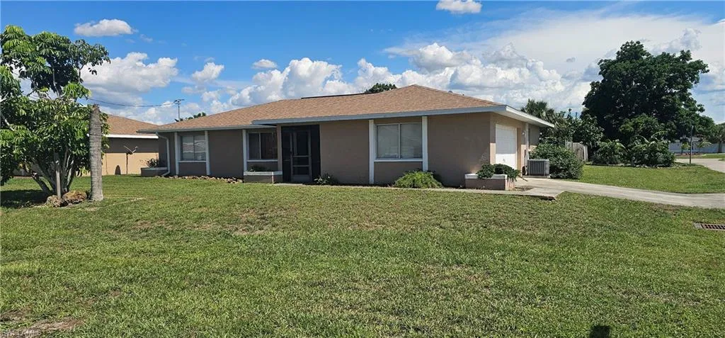 View of front of property featuring stucco siding, a front lawn, an attached garage, and driveway