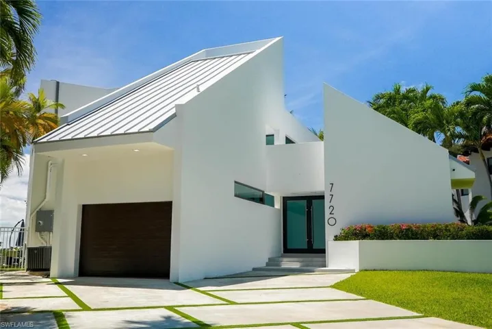 Contemporary house with a standing seam roof, an attached garage, stucco siding, and driveway